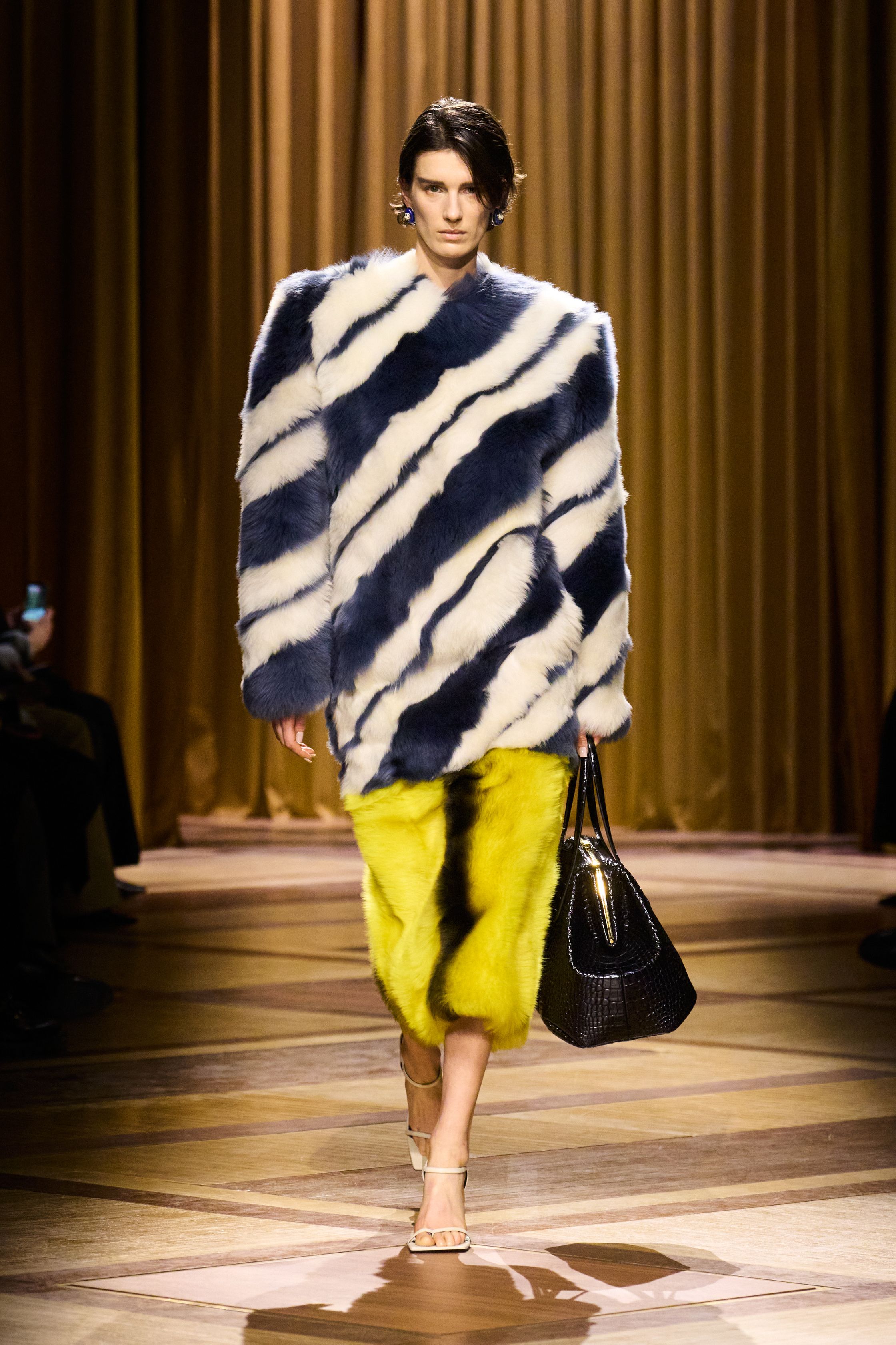 Mugler 本季继续强化品牌最核心的雕塑性感：极端肩线、收紧腰部与流畅长裤塑造出未来感女性轮廓。紫色权力套装、金属光泽衬衫和皮革裙装让整场秀既强势又华丽，仿佛科幻电影中的都市女主角-顽石频道趋势研究